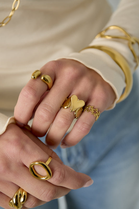 Goudkleuringe hartjes ring om de vinger van een vrouw